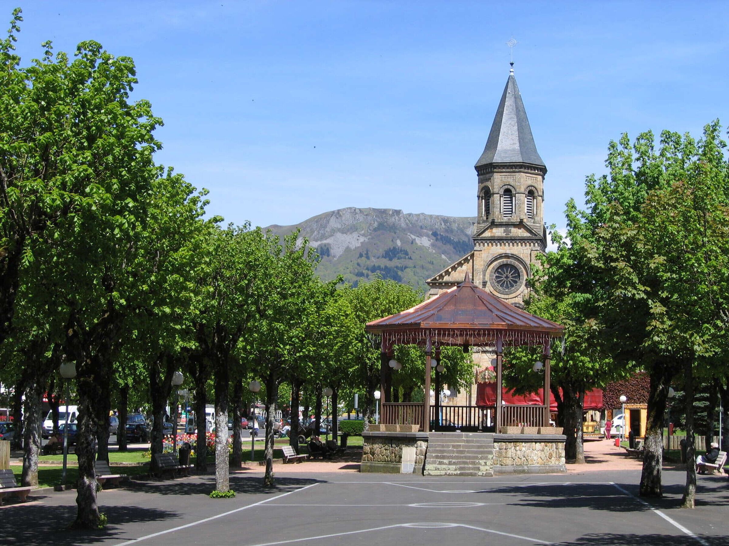 A gazebo in a park with a church in the background.