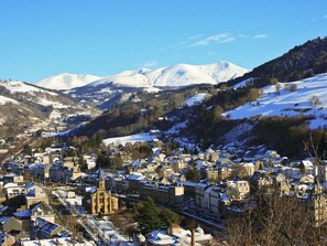Une ville où les bâtiments sont recouverts de neige et où se dresse une église remarquable, dotée d’un clocher abritant une horloge.