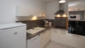 A modern kitchen with white cabinets, a Bosch dishwasher, a sink, a coffee maker, a microwave, and a stove. - Mont-Dore T2 with West Terrace and Wi-Fi (Mont-Dore)