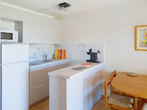 Cozinha compacta com geladeira, micro-ondas e cafeteira.