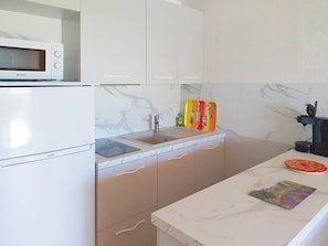 Eine Küche mit weißen Schränken, einer Mikrowelle, einem Spülbecken und einer Arbeitsplatte mit einer Zeitschrift.
