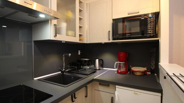 A modern kitchen with a built-in microwave, a coffee maker, and a dishwasher.
