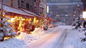 A snow-covered street with shops and a sign for 'THERMES' in the background.