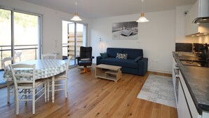 En moderne opholdsstue med spiseplads, sofa og køkken.