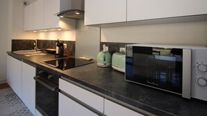 Et moderne køkken med indbygget komfur, mikroovn, elkedel og brødrister.