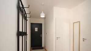 En gang med en sort dør, en hvid dør og et spejl på væggen.