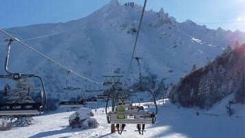 Een skilift met stoeltjes die een besneeuwde helling opgaan, met een berg op de achtergrond en een heldere lucht.