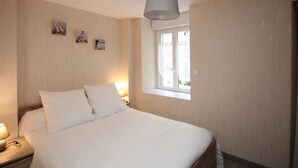 A bedroom with a bed, bedside lamps, a window, and wall-mounted artwork.