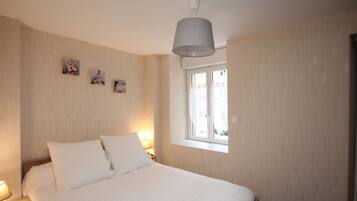 A bedroom with a bed, bedside lamps, a window, and wall-mounted artwork.