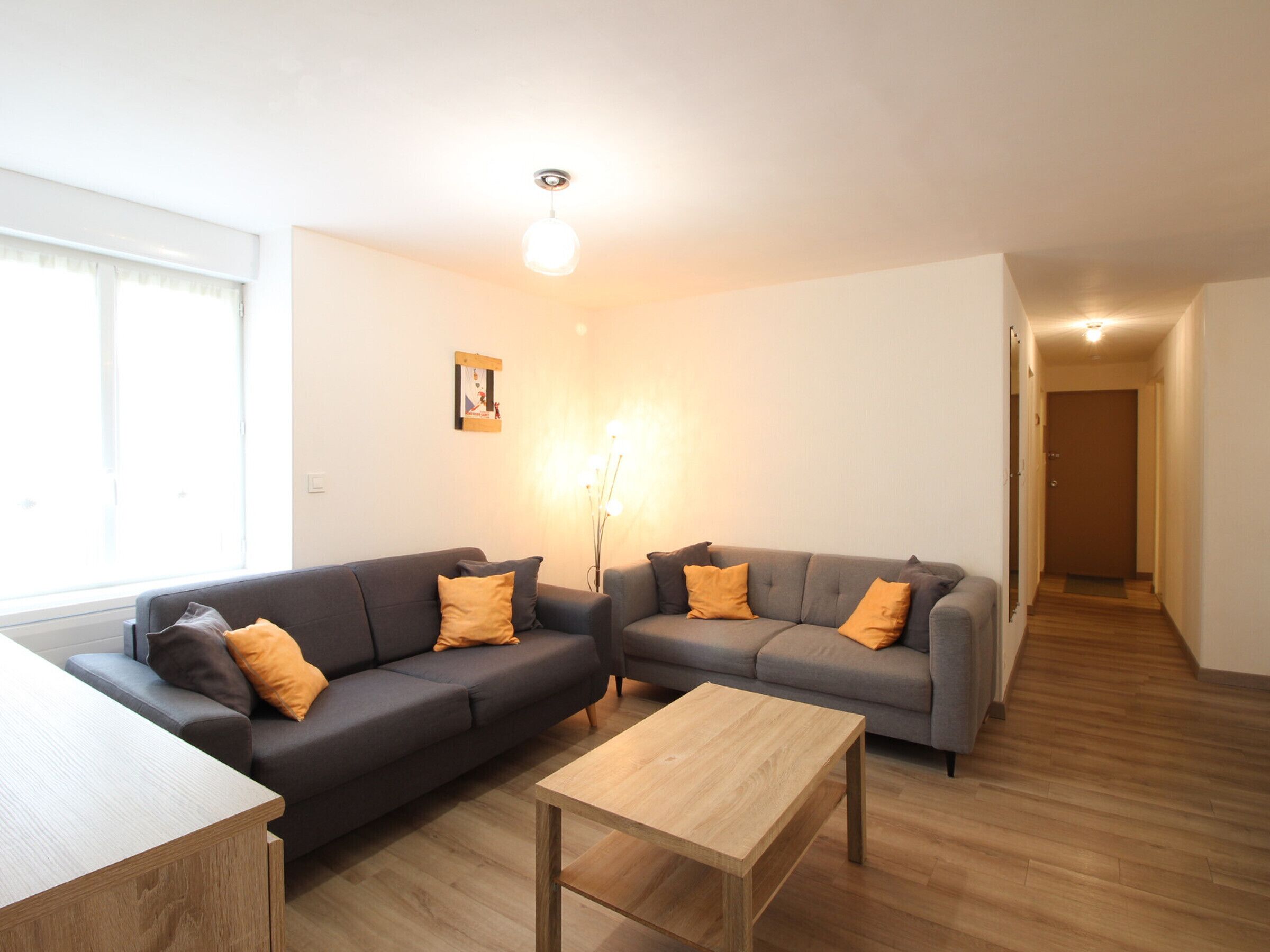 Una sala moderna con dos sofás grises, una mesa de centro de madera y un cuadro en la pared.