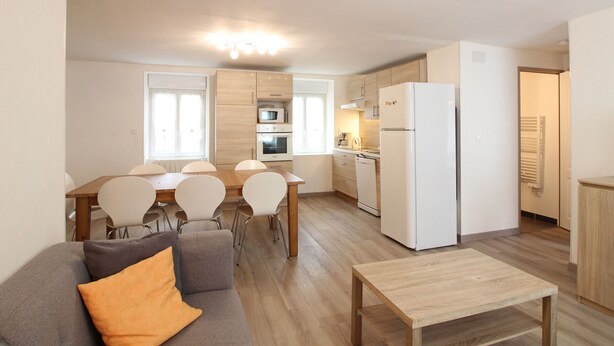 A modern apartment with a dining area, kitchen, and living space.