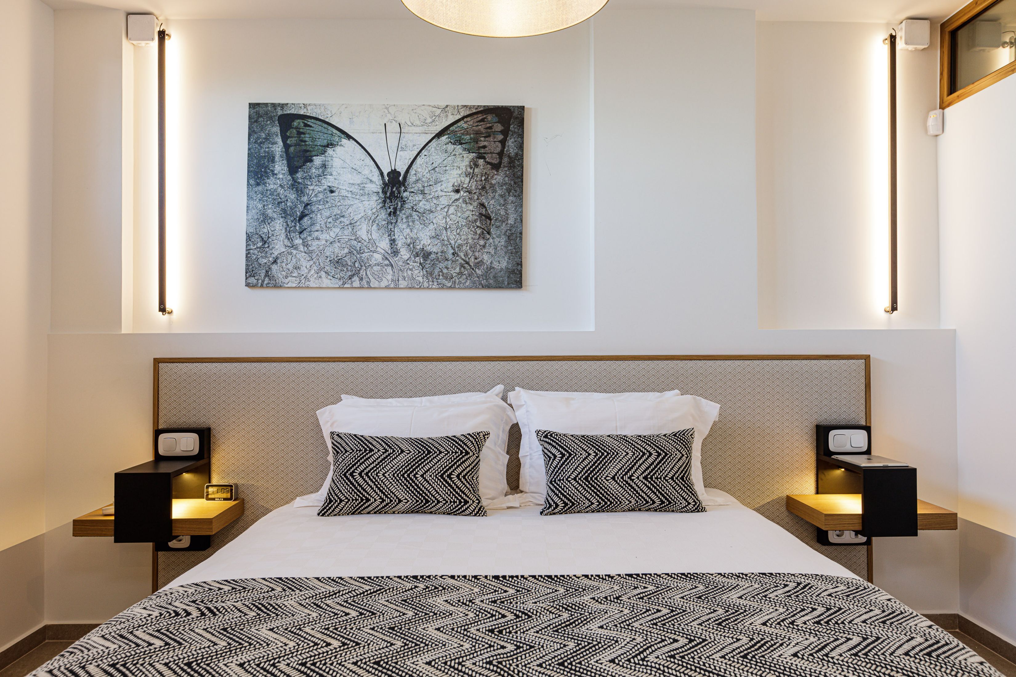 Ein modernes Hotelzimmer mit einem großen Bett, zwei Nachttischen und einem Wandbild.