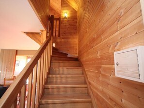 Eine Holztreppe mit Handlauf, die zu einer Zwischenebene mit einer Lampe führt.