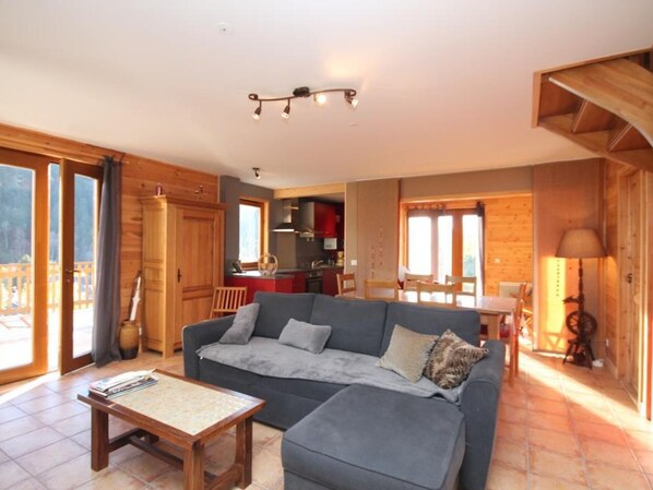 A cozy living room with a sofa, coffee table, and a view of the kitchen and dining area.