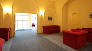 Una hall d'albergo con un'imponente arcata, posti a sedere rossi e pavimento in moquette.