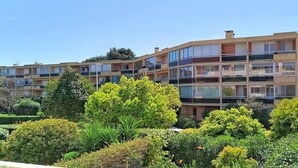 A multi-story residential building with balconies, surrounded by well-maintained greenery.