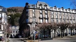 A large, historic building with multiple stories and a symmetrical facade. - CENTRE MONT-DORE - BEL APPARTEMENT T2 + MEZZANINE (Mont-Dore)