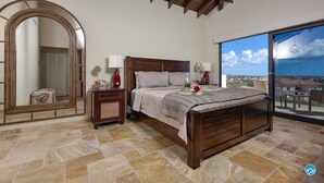 Een slaapkamer met een groot bed, een nachtkastje, een spiegel en uitzicht op het groen.