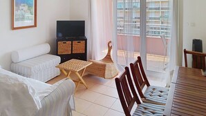 Una sala de estar con sofá, televisor, una mesita y un balcón con vistas.