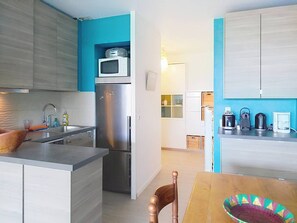 A compact kitchen with a microwave, refrigerator, and a dining area with a table and chairs.