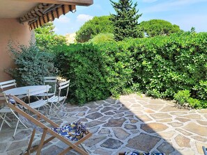 A patio with stone flooring, a table, chairs, and a bench.