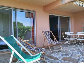 A patio with two lounge chairs, a table, and chairs.
