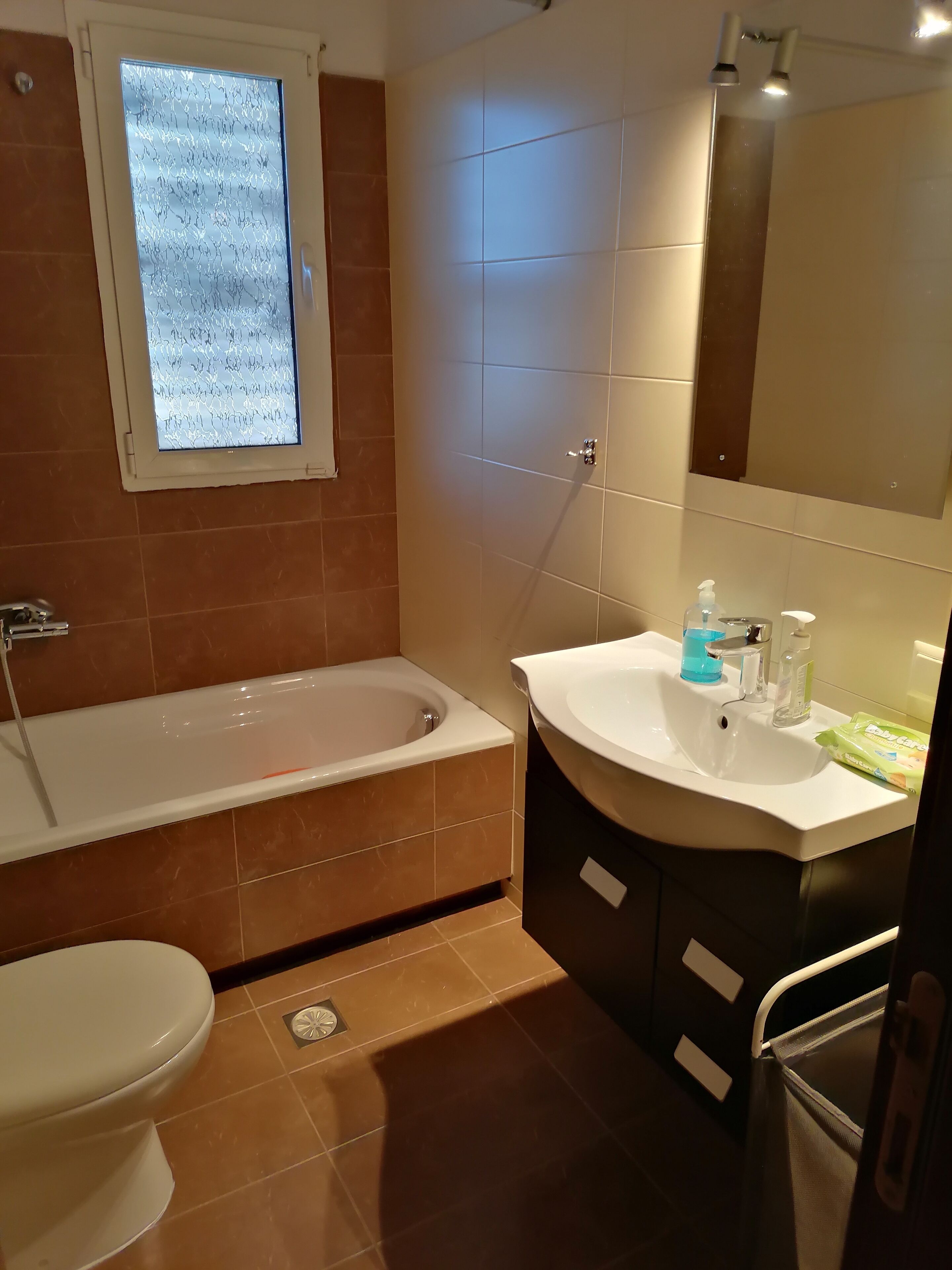 Een badkamer met een bad, toilet, wastafel en een raam.