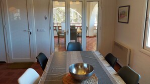 A dining area with a table set for four, a large bowl on the center, and a view of the outdoor patio with chairs and a table. - Villa Catabella with unlimited WiFi internet next to the beaches and the village (L'Escala)