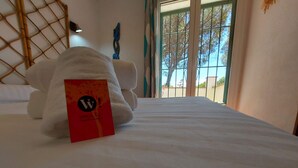 A neatly made bed with a red tag on the pillow, a bamboo headboard, and a view of trees through a window. - Villa Catabella with unlimited WiFi internet next to the beaches and the village (L'Escala)