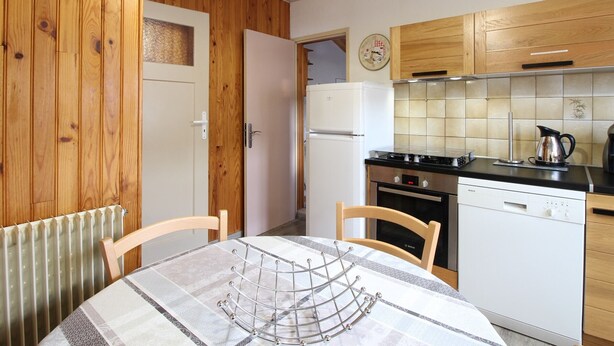 A compact kitchen with wooden cabinets, a refrigerator, a stove, and a dishwasher. - Chalet 6 rooms, sleeps 8, near center, WIFI (Mont-Dore)