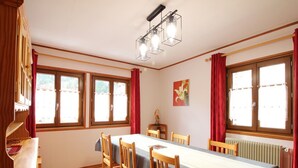 A dining room with a long table, wooden chairs, and a radiator. - Chalet 6 rooms, sleeps 8, near center, WIFI (Mont-Dore)