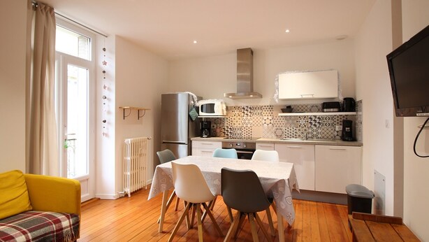 Una cocina moderna con comedor, un sillón amarillo y un televisor.