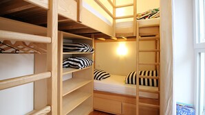 Dormitorio con literas, estantes de madera y una ventana.