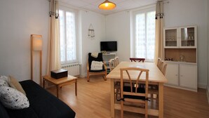 A modern living room with a dining area, a sofa, a TV, and a kitchen with cabinets. - Bright apartment in La Bourboule, 3 bedrooms, near center (La Bourboule)