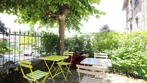 An outdoor seating area with yellow and white chairs and tables, surrounded by greenery and a metal fence. - Bright apartment in La Bourboule, 3 bedrooms, near center (La Bourboule)