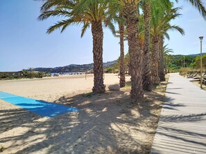 A beach with a wooden walkway, palm trees, and a clear blue sky. - Spacious 2-Bed Cabin Apartment Near Beach & Shops, Large Loggia, Garage Included (Bormes-les-Mimosas)