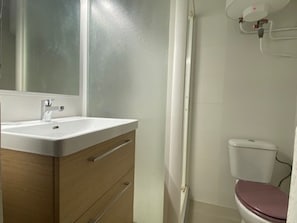 A bathroom with a white sink, wooden vanity, and a toilet.