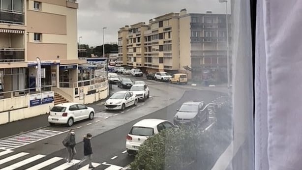 Ein mehrstöckiges Gebäude mit einer Fußgängerzone und parkenden Autos.