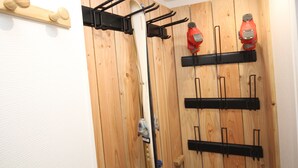 A room with wooden panel walls, a black metal rack with hooks, and a wooden shelf with two red objects. - Mont-Dore: Central T3 Apartment with Wifi (Mont-Dore)