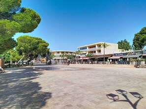 A public square with a fountain, shops, and a building with signage.