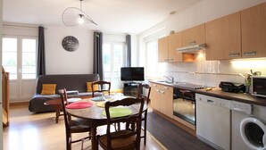 Una cocina moderna con armarios de madera, lavavajillas integrado y comedor con mesa y sillas redondas.