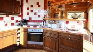 A kitchen with wooden cabinets, a tiled backsplash, and a built-in oven. - Spacious 3* chalet with parking and WiFi in Mont Dore (Mont-Dore)