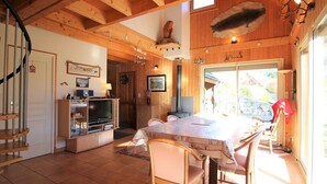 A wooden interior with a dining table, chairs, a fireplace, and a staircase. - Spacious 3* chalet with parking and WiFi in Mont Dore (Mont-Dore)