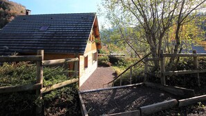 A wooden cabin with a sloped roof, surrounded by a wooden fence and a gravel path leading to the entrance. - Spacious 3* chalet with parking and WiFi in Mont Dore (Mont-Dore)