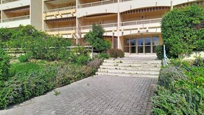 A multi-story building with a central entrance, surrounded by greenery and a paved walkway.