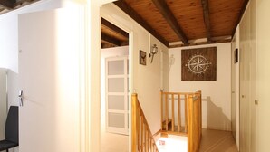 A hallway with a wooden staircase, a white door, and a compass wall decoration. - Beautiful T3 Duplex with Balcony, Wifi and Parking 300m from Center (Mont-Dore)
