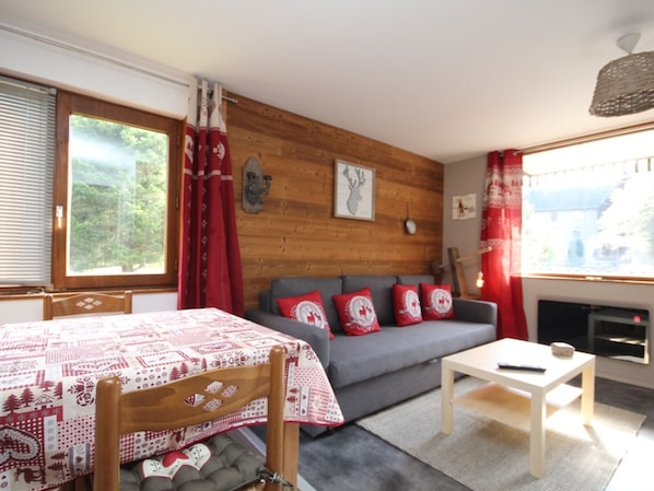 A cozy room with a bed, a sofa, a small table, and a fireplace.