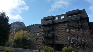 A multi-story building with a modern architectural design, featuring balconies and large windows. - Charming T2 with balcony in Mont Dore, parking included (Mont-Dore)