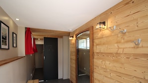 A hallway with wooden paneling, a bench, a door with a mirror, and a red towel hanging on the wall. - Mont-Dore, renovated 2-bedroom with garden, parking, wifi (Mont-Dore)