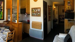 Ett kompakt bostadsutrymme med ett litet kök, en matplats och en soffa.
